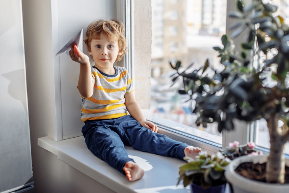 Dítě sedící na okenním parapetu